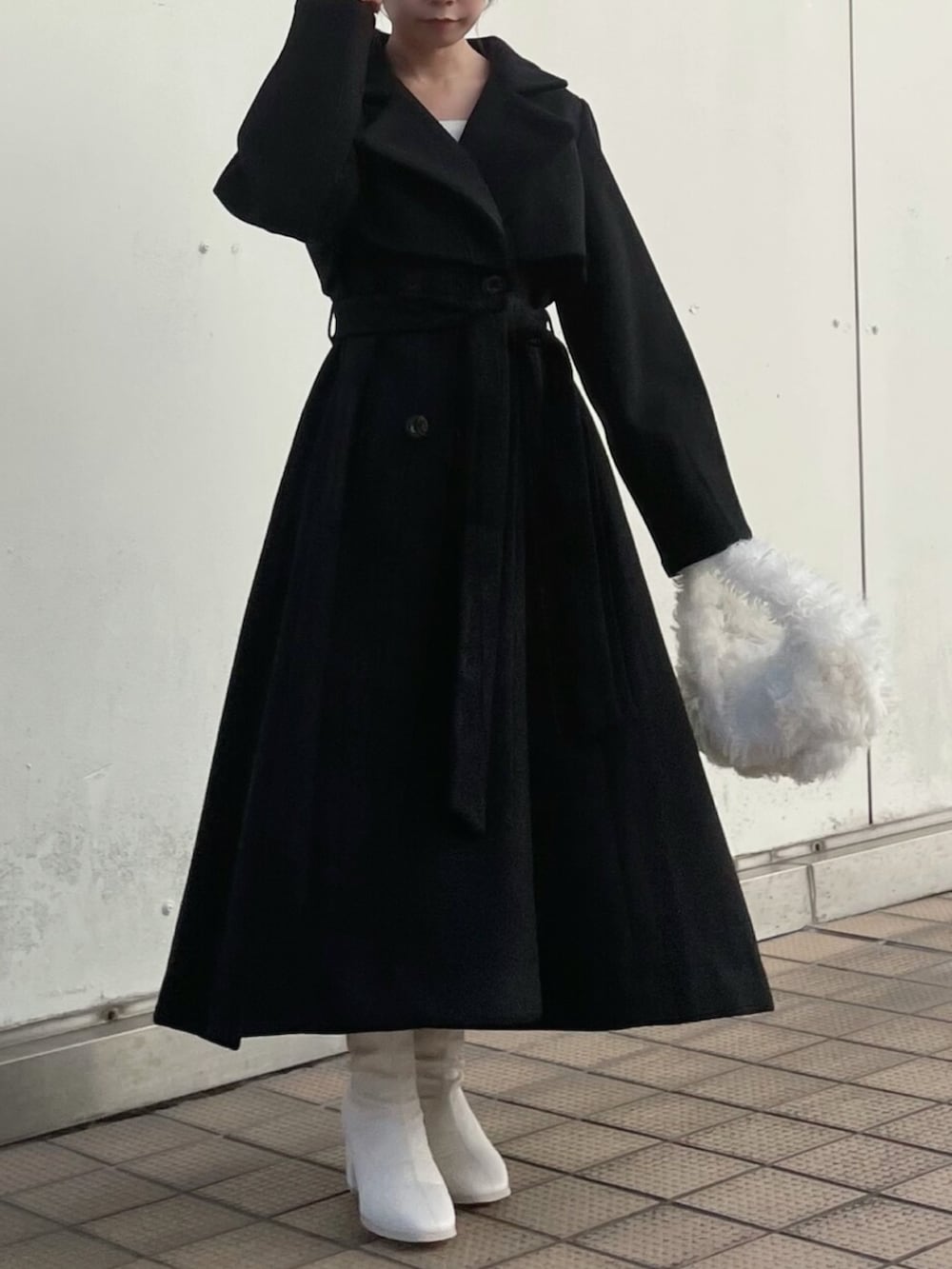 ホワイト系のハンドバッグ、ブラック系のトレンチコート、ホワイト系のブーツを着用したレディースの秋コーディネートの4枚目の写真