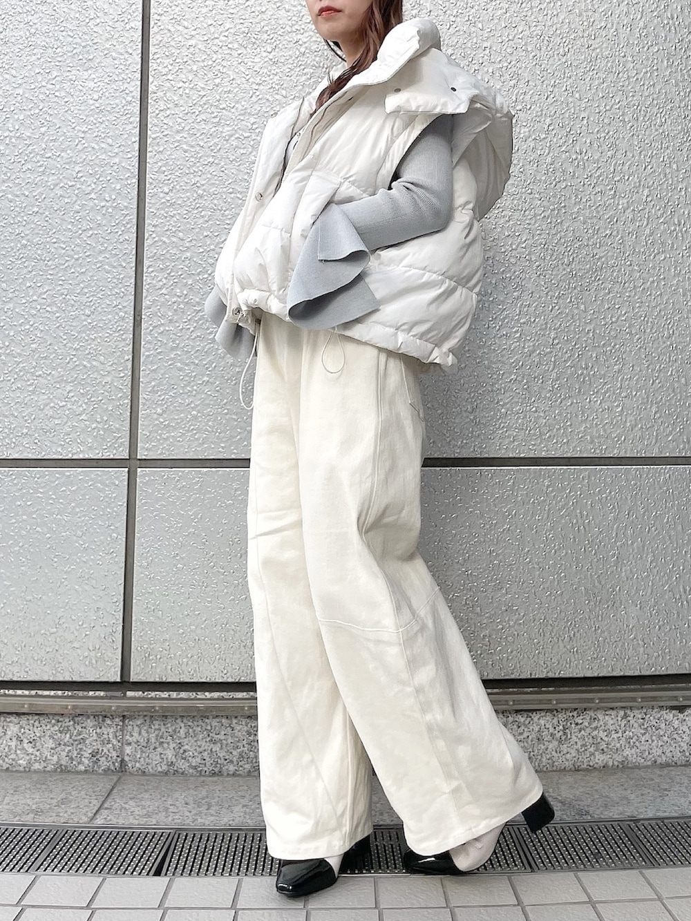 グレー系のニット/セーター、ホワイト系のダウンジャケット/コート、ホワイト系のデニムパンツを着用したレディースの冬コーディネートの3枚目の写真