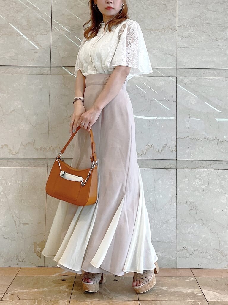 ブラウン系のハンドバッグ、ホワイト系のシャツ/ブラウス、ベージュ系のサンダルを着用したレディースの夏コーディネートの2枚目の写真