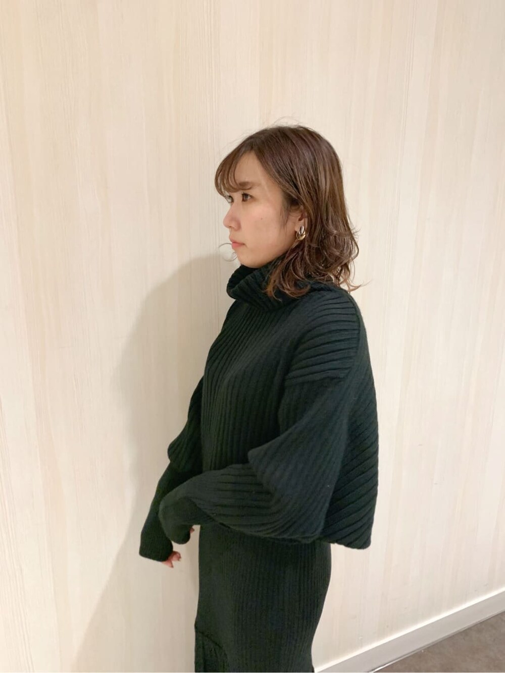 ブラック系のスカート、ブラック系のブーツ、ブラック系のニット/セーターを着用したレディースの秋コーディネートの6枚目の写真