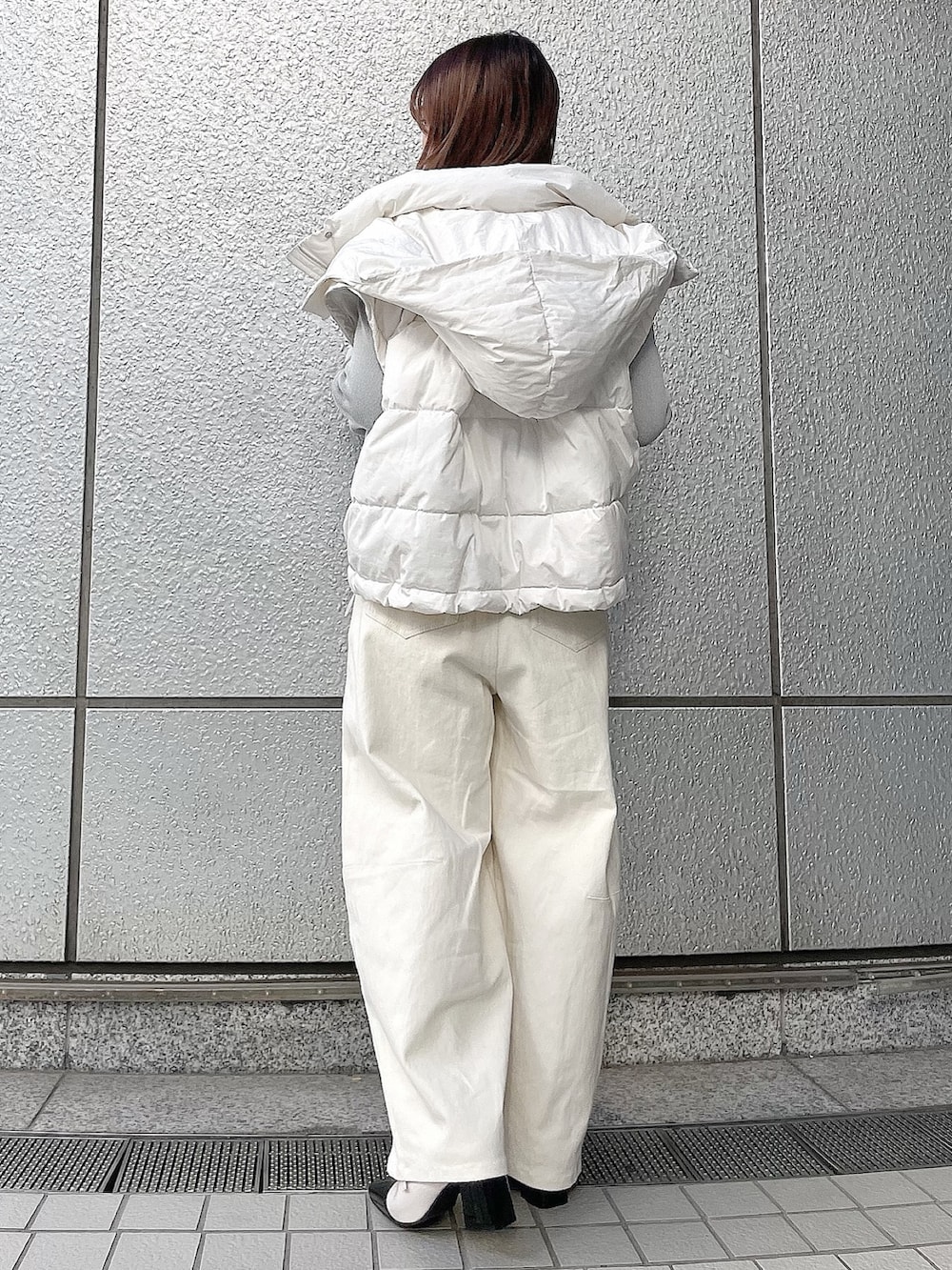 グレー系のニット/セーター、ホワイト系のダウンジャケット/コート、ホワイト系のデニムパンツを着用したレディースの冬コーディネートの5枚目の写真