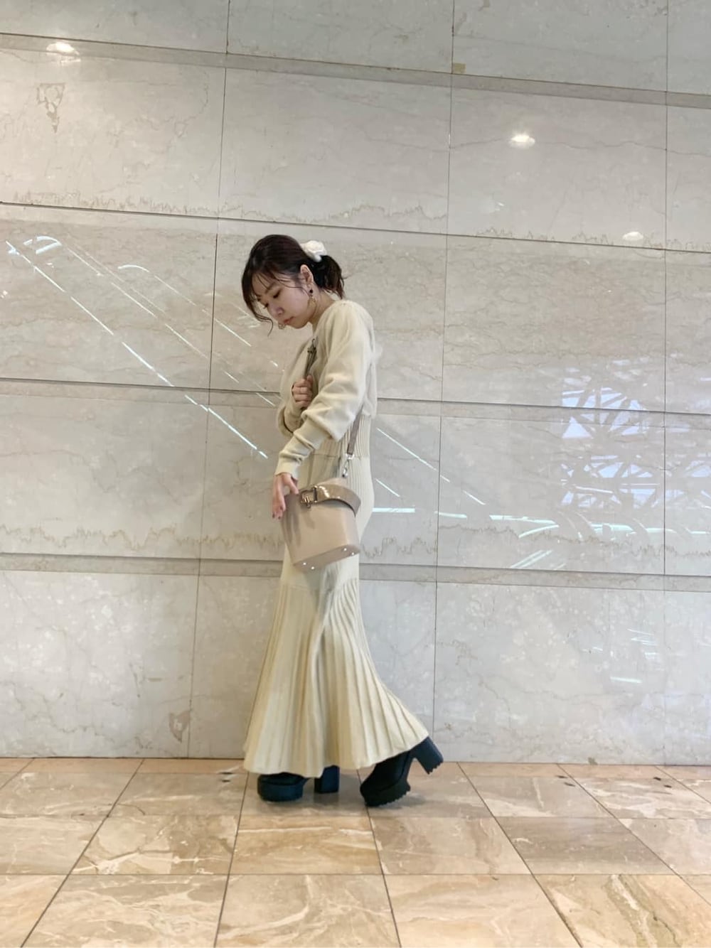 ブラック系のブーツ、ブラウン系のチェスターコート、ベージュ系のワンピースを着用したレディースの冬コーディネートの2枚目の写真