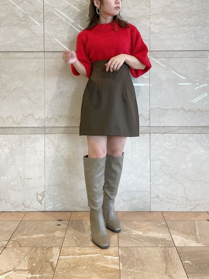 レッド系のニット/セーター、ブラウン系のスカート、ベージュ系のブーツを着用したレディースの秋コーディネートの4枚目の写真