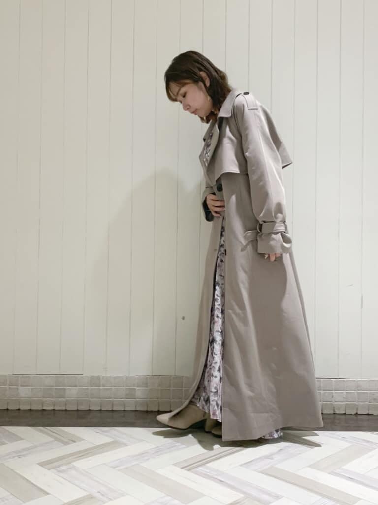 グレー系のトレンチコート、ピンク系のワンピース、ベージュ系のブーツを着用したレディースの秋コーディネートの4枚目の写真