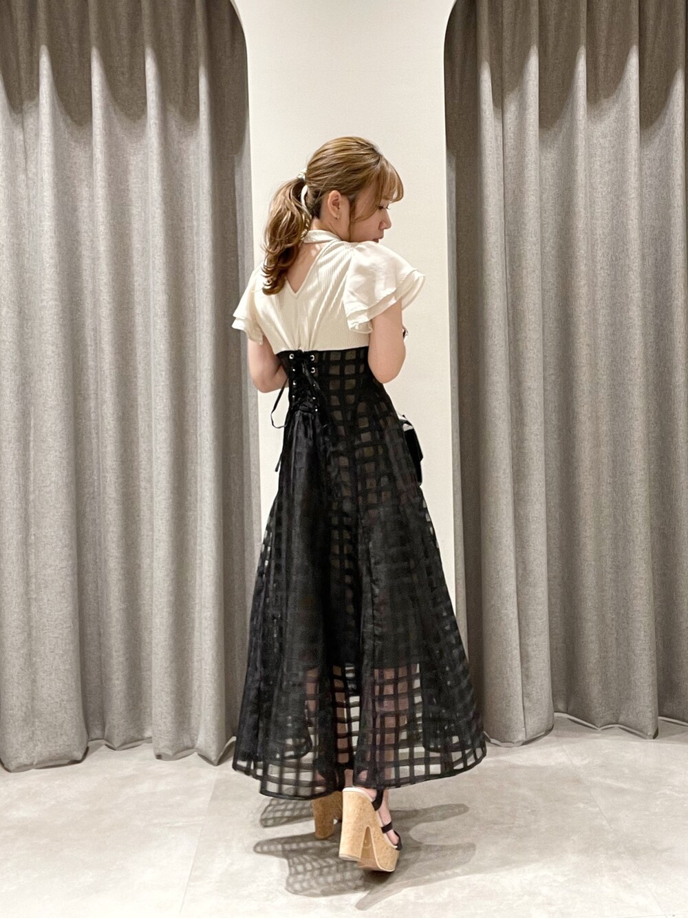 ホワイト系のワンピース、ブラック系のハンドバッグ、ブラック系のサンダルを着用したレディースの夏コーディネートの2枚目の写真