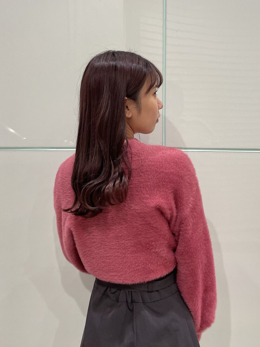 ピンク系のニット/セーター、グレー系のスカート、ブラック系のブーツを着用したレディースの秋コーディネートの7枚目の写真