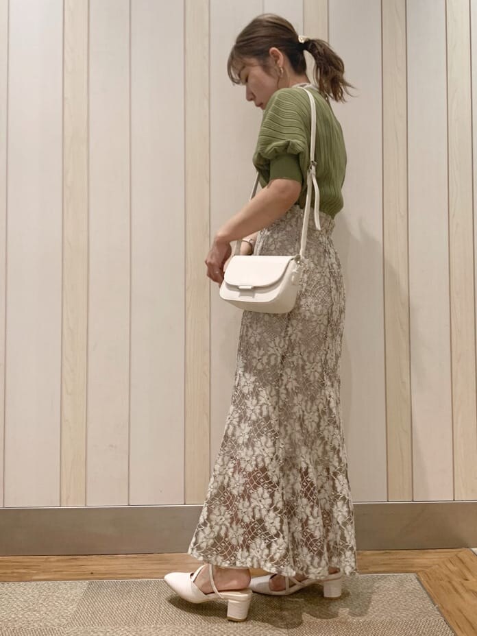 ベージュ系のスカート、ホワイト系のパンプス、グリーン系のニット/セーターを着用したレディースの春コーディネートの2枚目の写真