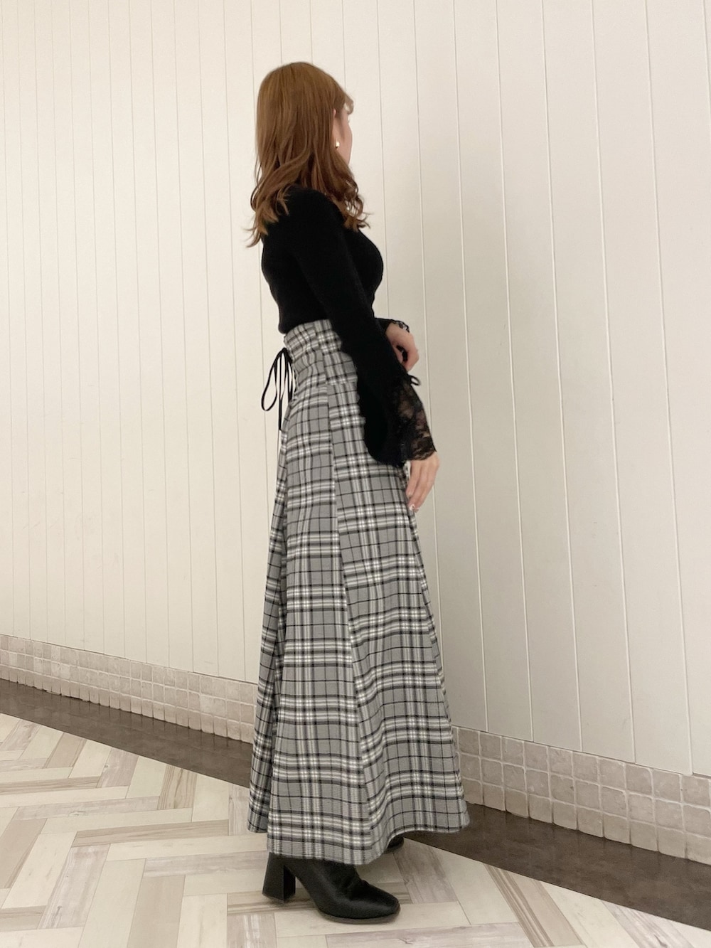 ブラック系のニット/セーター、グレー系のスカート、ブラック系のブーツを着用したレディースの秋コーディネートの2枚目の写真