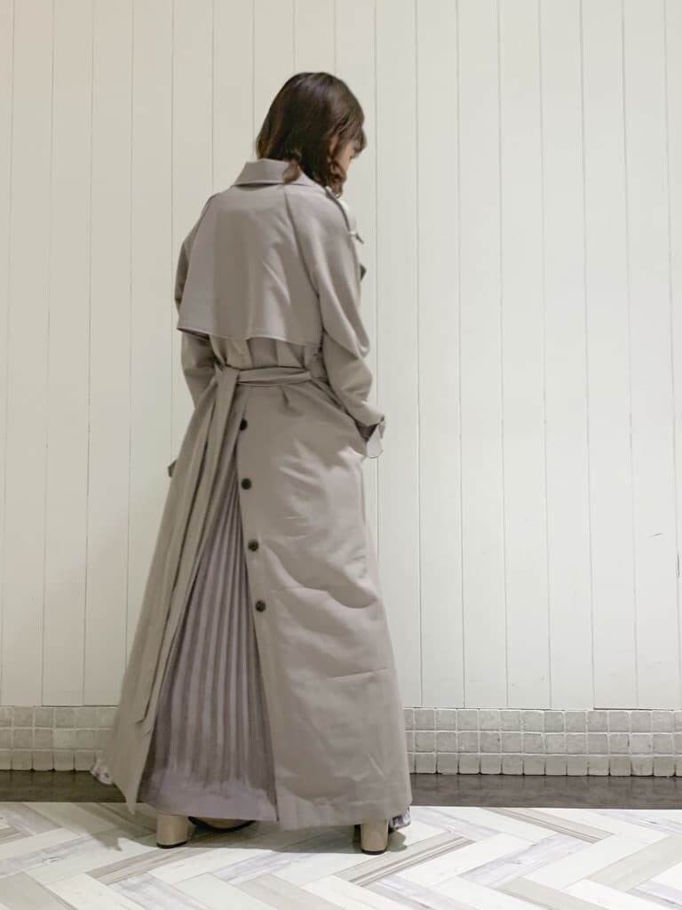 グレー系のトレンチコート、ピンク系のワンピース、ベージュ系のブーツを着用したレディースの秋コーディネートの3枚目の写真