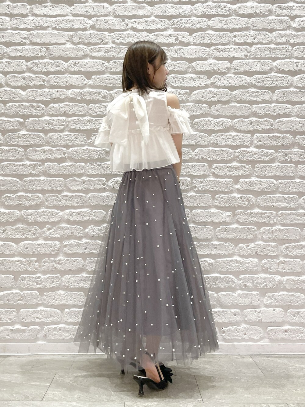 ホワイト系のTシャツ/カットソー、ブラック系のパンプス、ブラック系のハンドバッグを着用したレディースの夏コーディネートの3枚目の写真