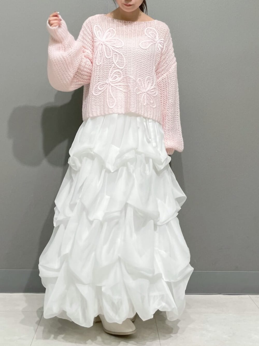 ピンク系のニット/セーター、ホワイト系のスカート、ホワイト系のブーツを着用したレディースの秋コーディネートの4枚目の写真