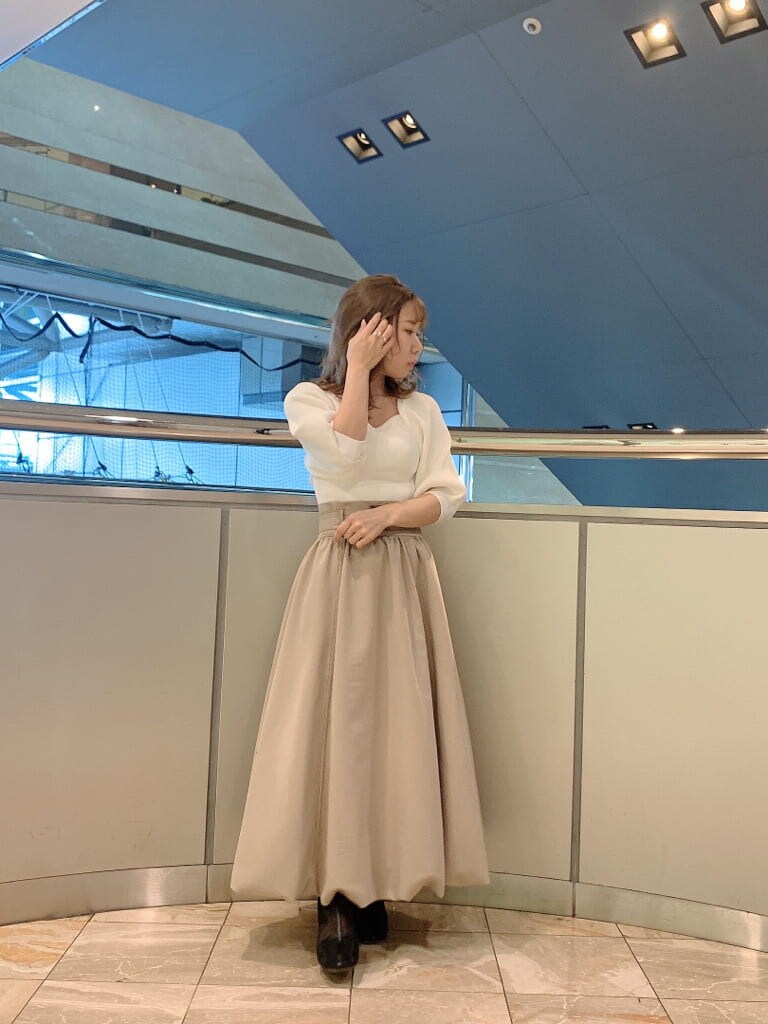 ベージュ系のスカート、ホワイト系のニット/セーター、ブラック系のブーツを着用したレディースの冬コーディネートの2枚目の写真