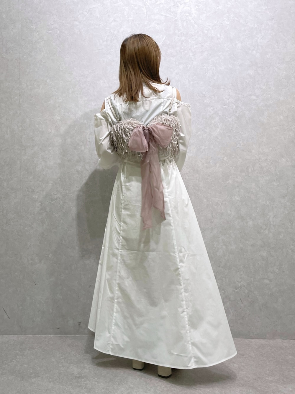 ホワイト系のシャツワンピース、ピンク系のキャミソール、ベージュ系のブーツを着用したレディースの秋コーディネートの3枚目の写真