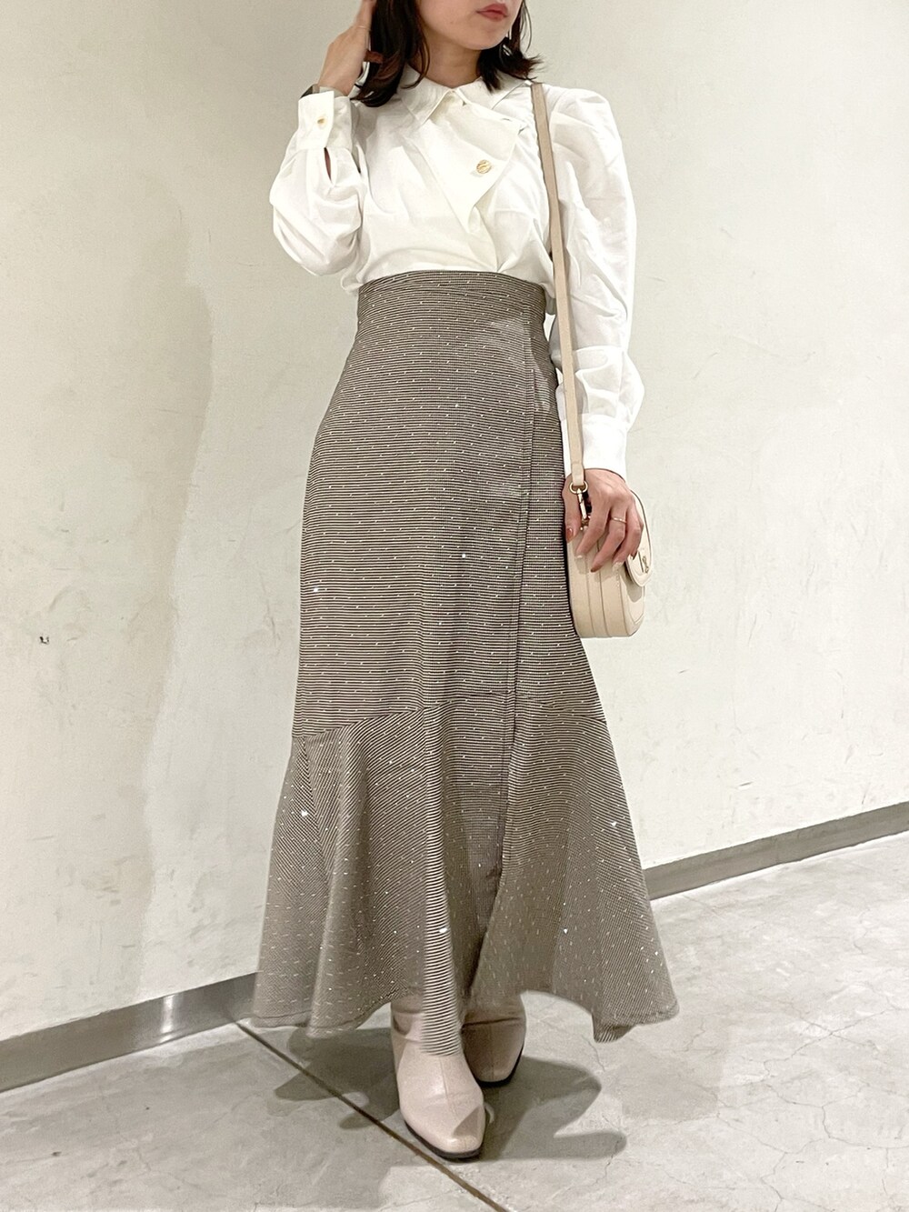 ホワイト系のシャツ/ブラウス、ブラウン系のスカート、ベージュ系のブーツを着用したレディースの秋コーディネートの6枚目の写真