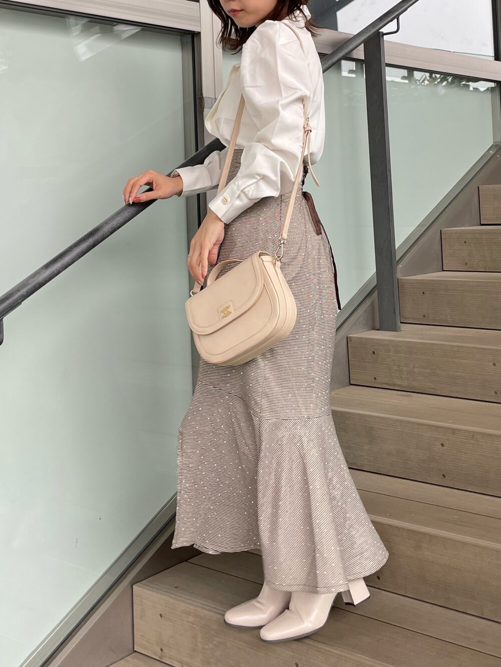 ホワイト系のシャツ/ブラウス、ブラウン系のスカート、ベージュ系のブーツを着用したレディースの秋コーディネートの3枚目の写真