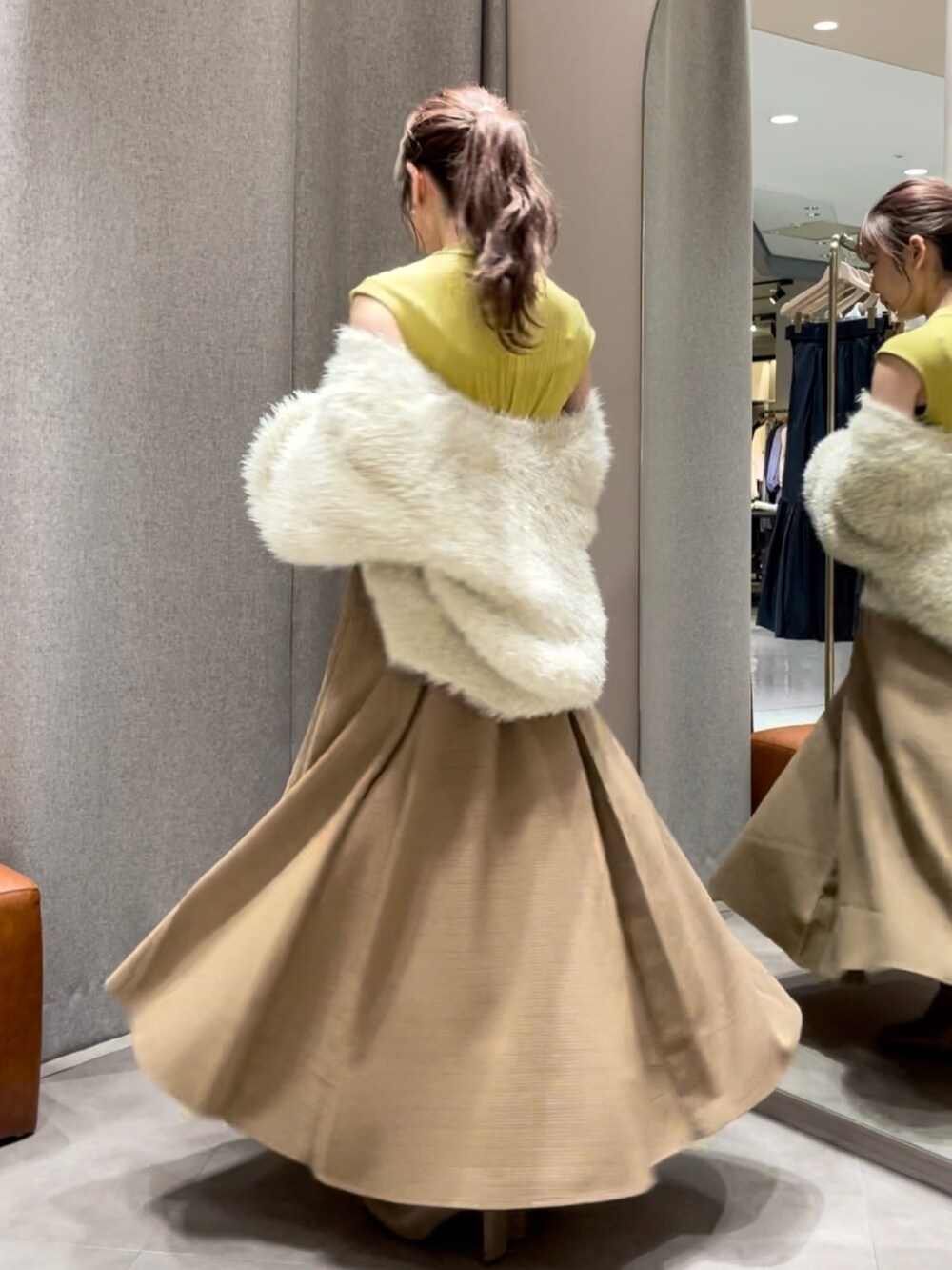 ベージュ系のカーディガン/ボレロ、イエロー系のワンピース、ベージュ系のブーツを着用したレディースの秋コーディネートの2枚目の写真