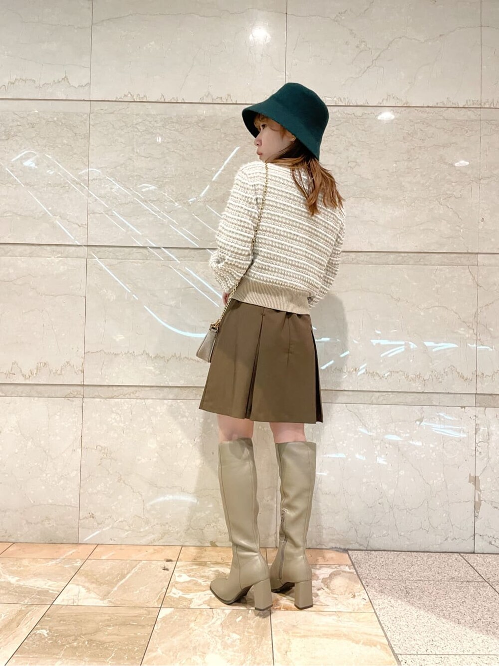 ブラウン系のスカート、ベージュ系のブーツ、ベージュ系のカーディガン/ボレロを着用したレディースの秋コーディネートの4枚目の写真