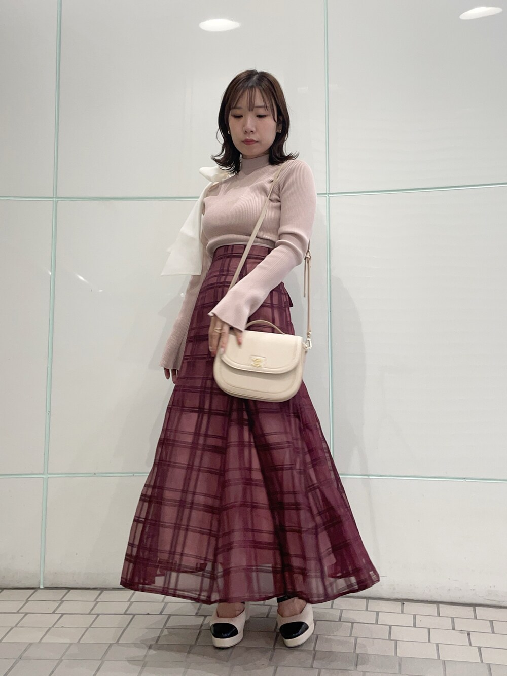 ピンク系のニット/セーター、レッド系のスカート、ホワイト系のハンドバッグを着用したレディースの秋コーディネートの4枚目の写真