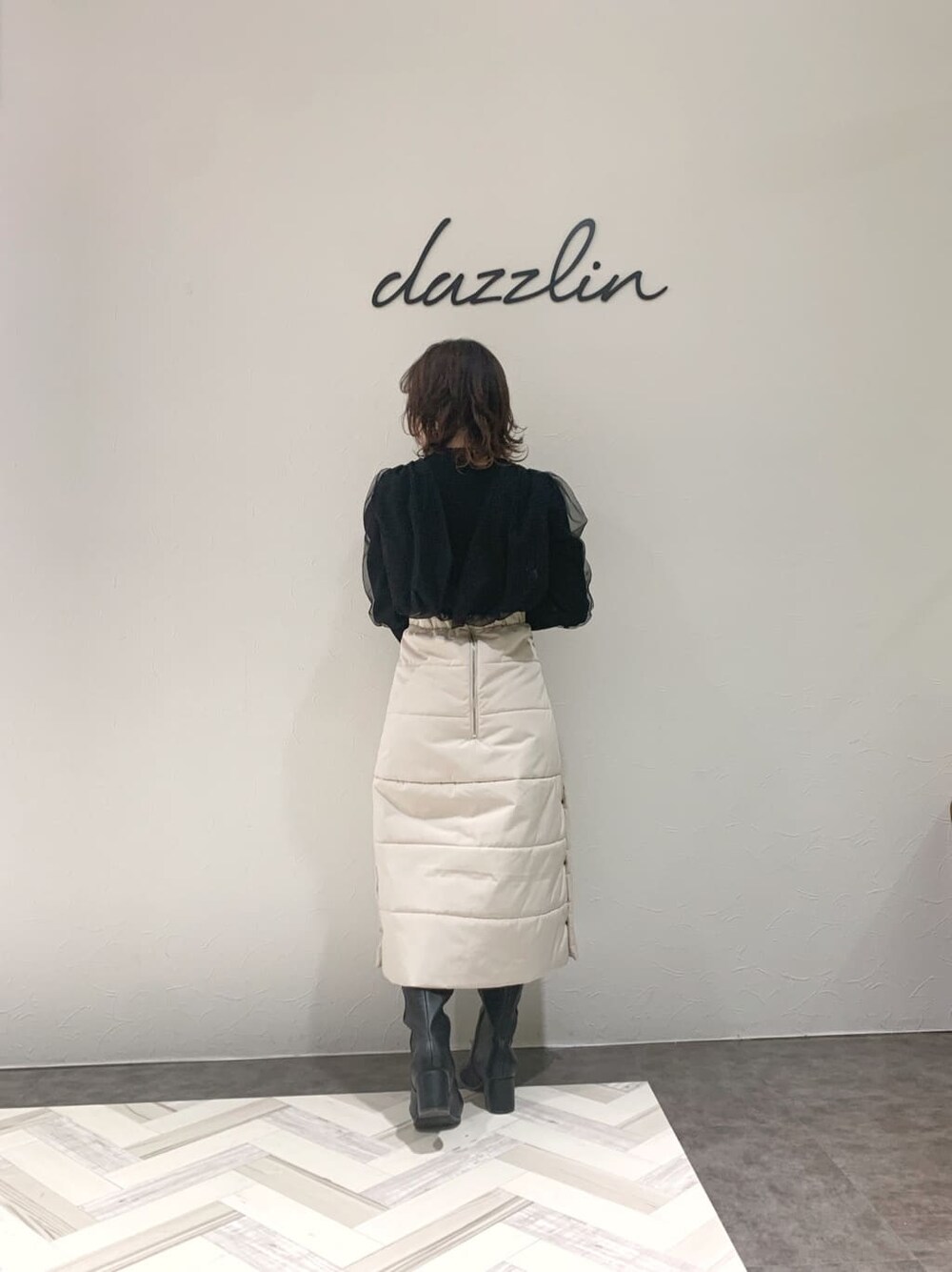 ブラック系のブーツ、ブラック系のニット/セーター、ホワイト系のスカートを着用したレディースの秋コーディネートの3枚目の写真