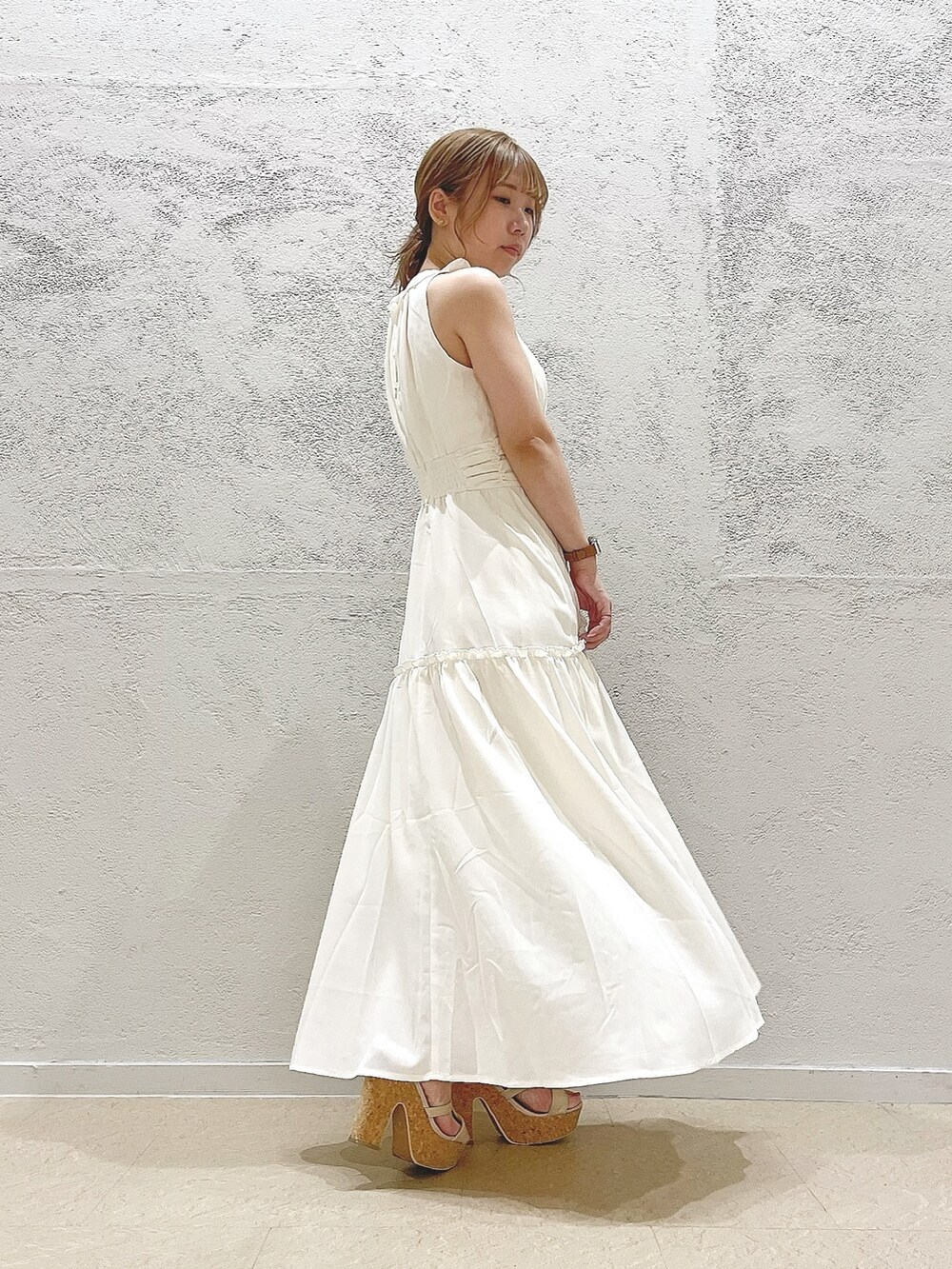 イエロー系のハンドバッグ、ホワイト系のサンダル、ホワイト系のワンピースを着用したレディースの夏コーディネートの2枚目の写真