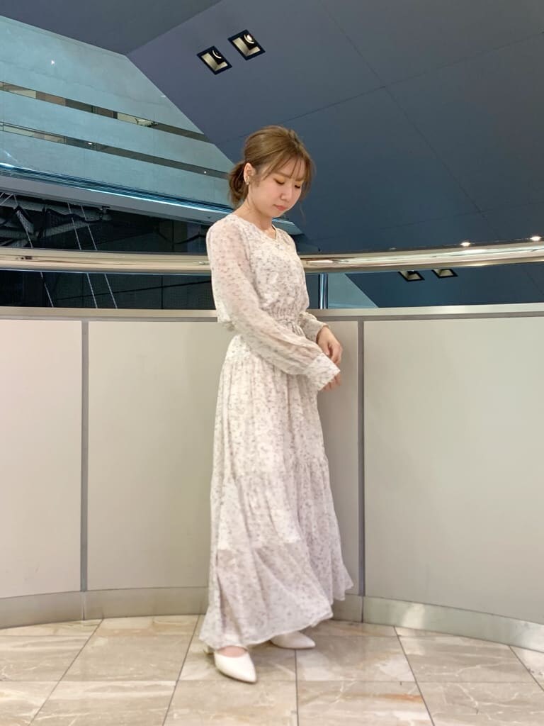 ベージュ系のトレンチコート、オレンジ系のワンピース、ホワイト系のパンプスを着用したレディースの冬コーディネートの2枚目の写真