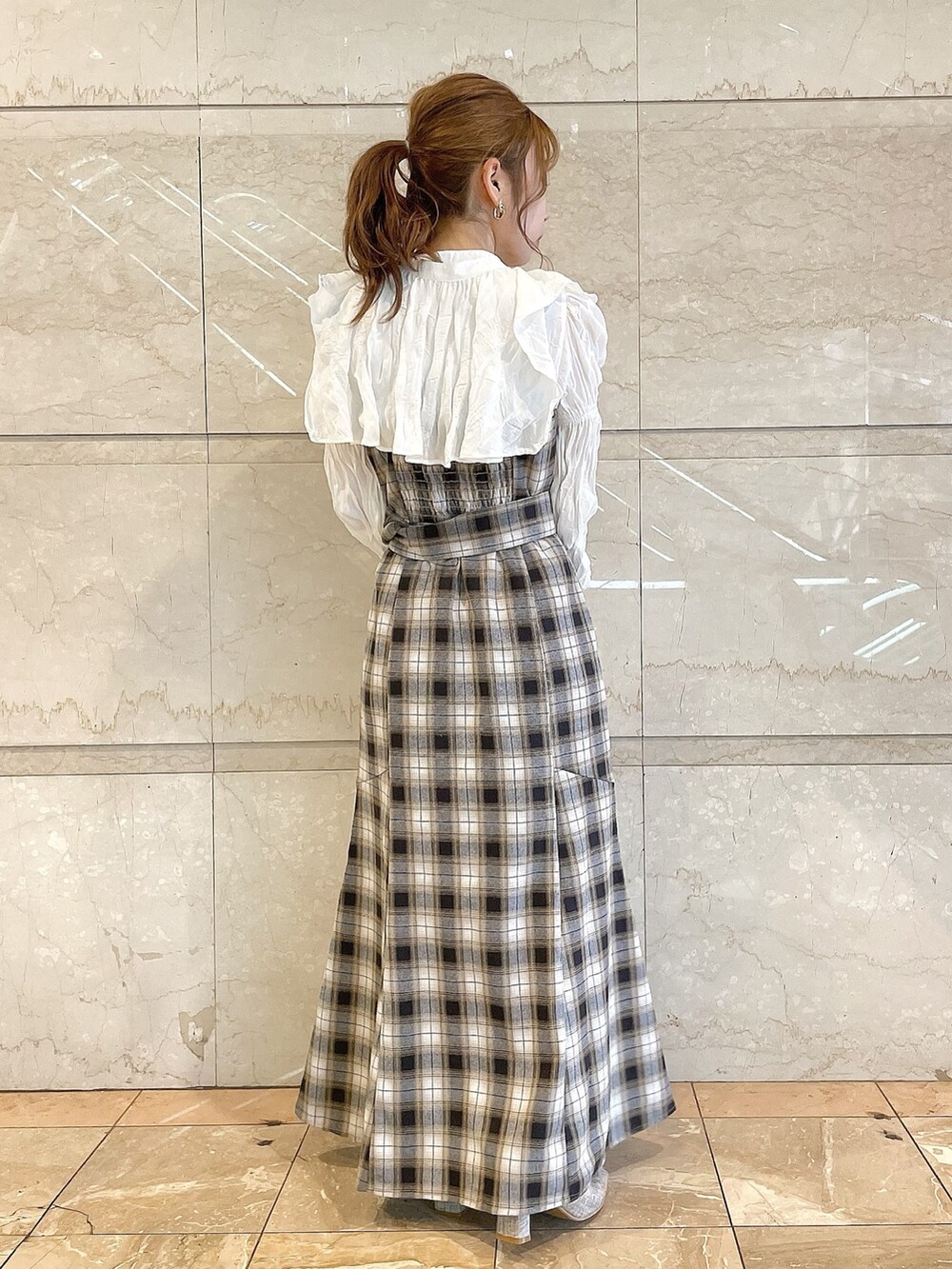 イエロー系のワンピース、グレー系のパンプスを着用したレディースの冬コーディネートの3枚目の写真