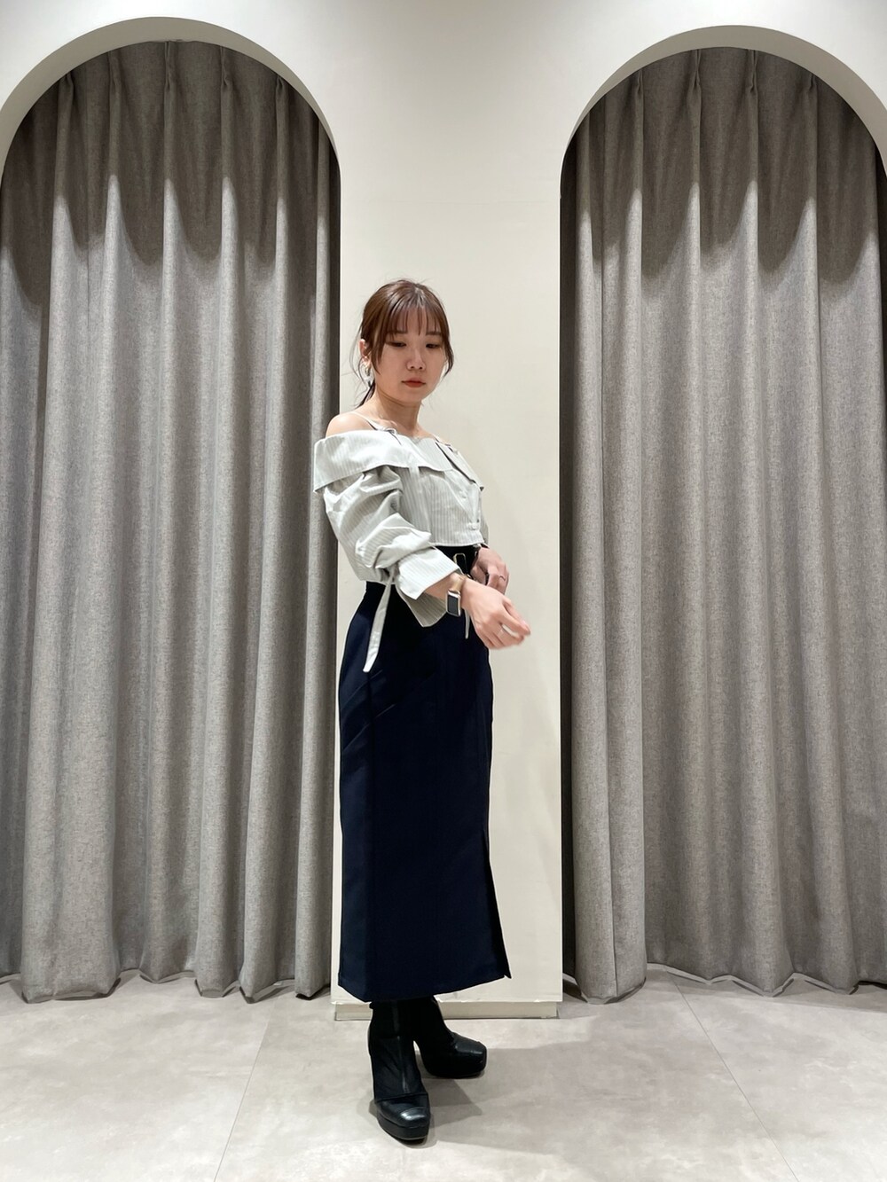 ブルー系のスカート、グレー系のシャツ/ブラウス、ブラック系のブーツを着用したレディースの春コーディネートの2枚目の写真