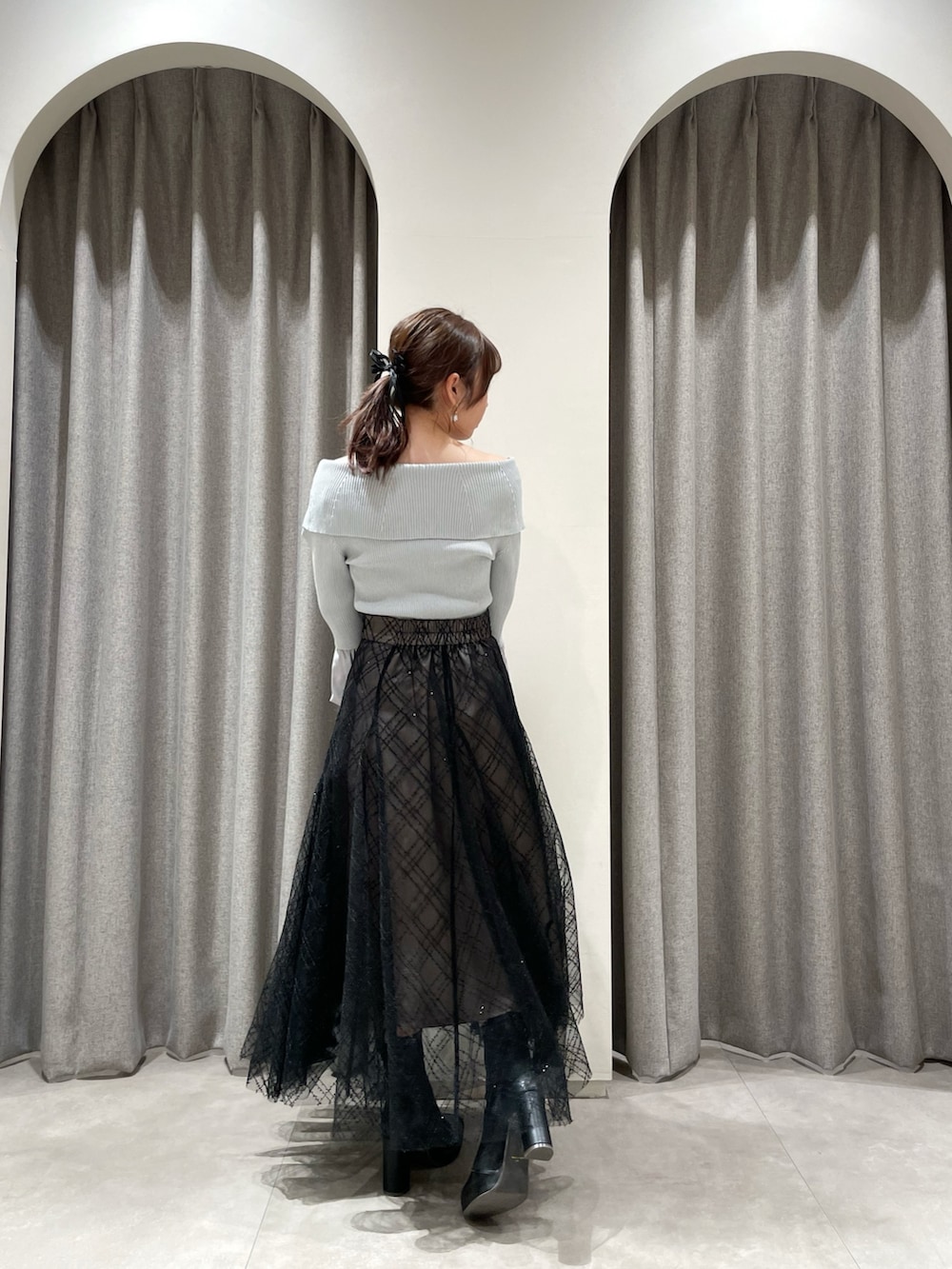 ブラック系のスカート、グレー系のニット/セーター、ブラック系のブーツを着用したレディースの春コーディネートの2枚目の写真