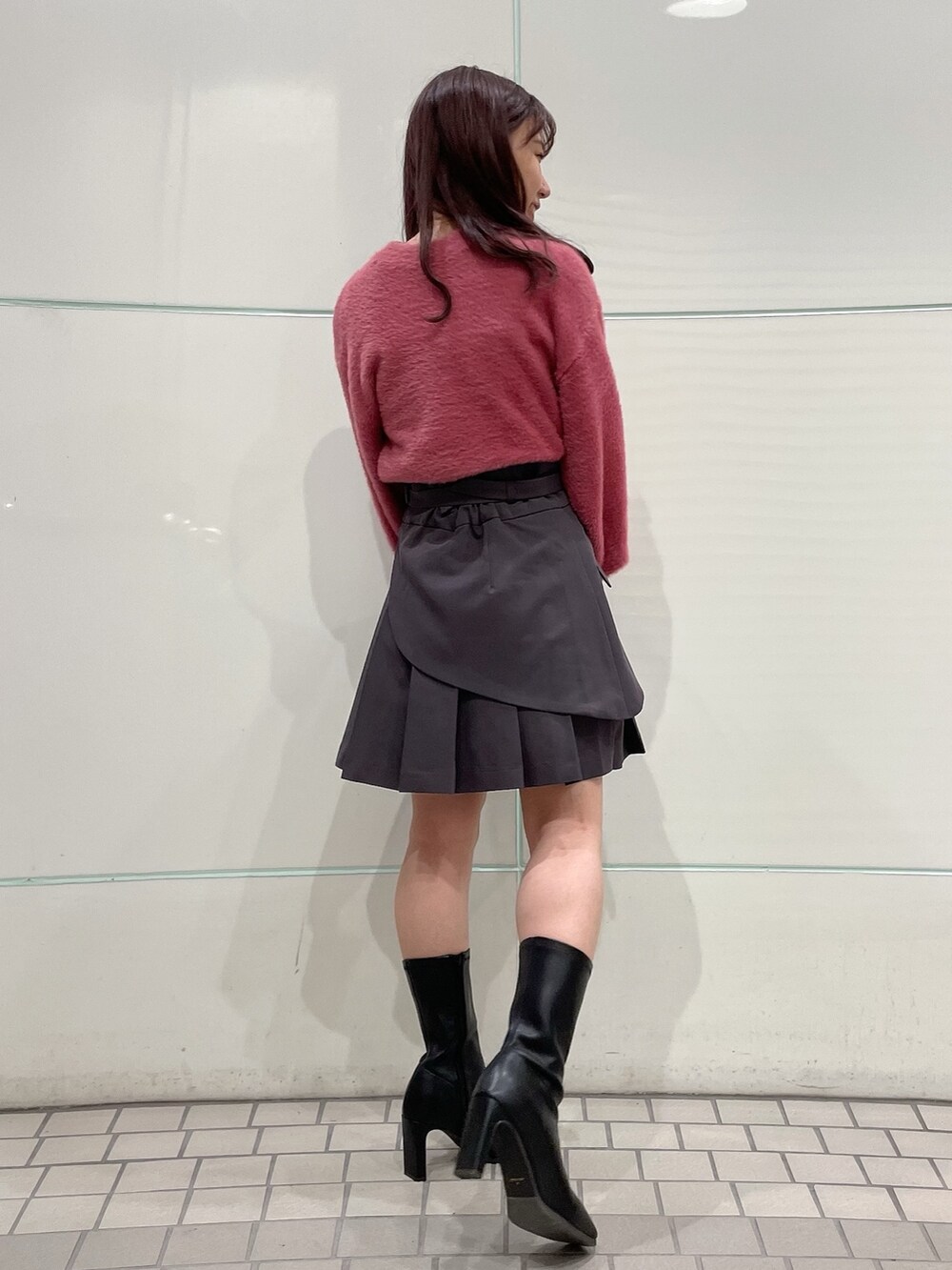 ピンク系のニット/セーター、グレー系のスカート、ブラック系のブーツを着用したレディースの秋コーディネートの3枚目の写真