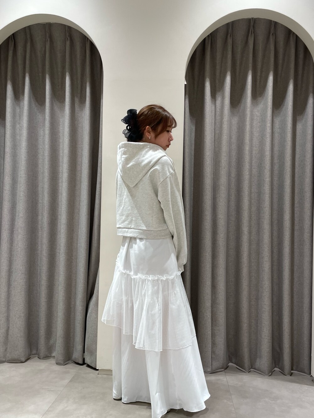 グレー系のパーカー、ホワイト系のスカート、ホワイト系のブーツを着用したレディースの春コーディネートの4枚目の写真