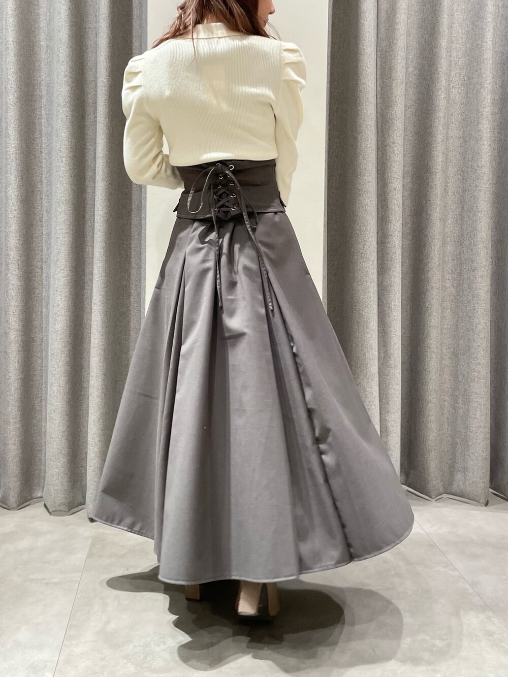 ホワイト系のニット/セーター、グレー系のスカート、ベージュ系のブーツを着用したレディースの冬コーディネートの2枚目の写真