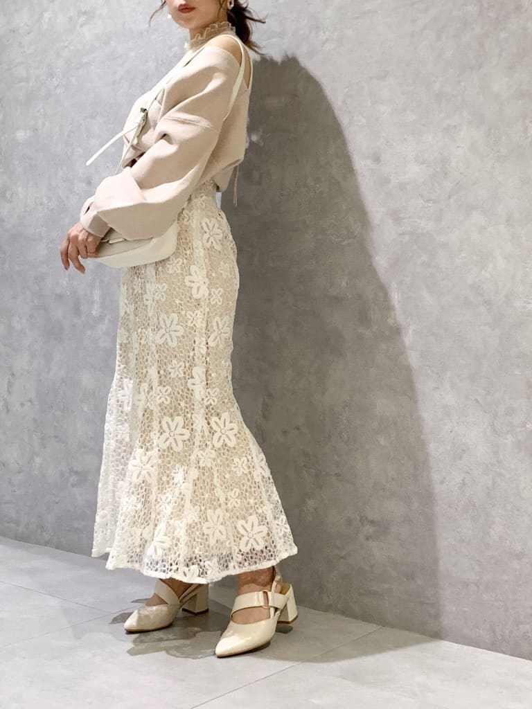 ホワイト系のスカート、ホワイト系のパンプス、ホワイト系のショルダーバッグを着用したレディースの春コーディネートの2枚目の写真