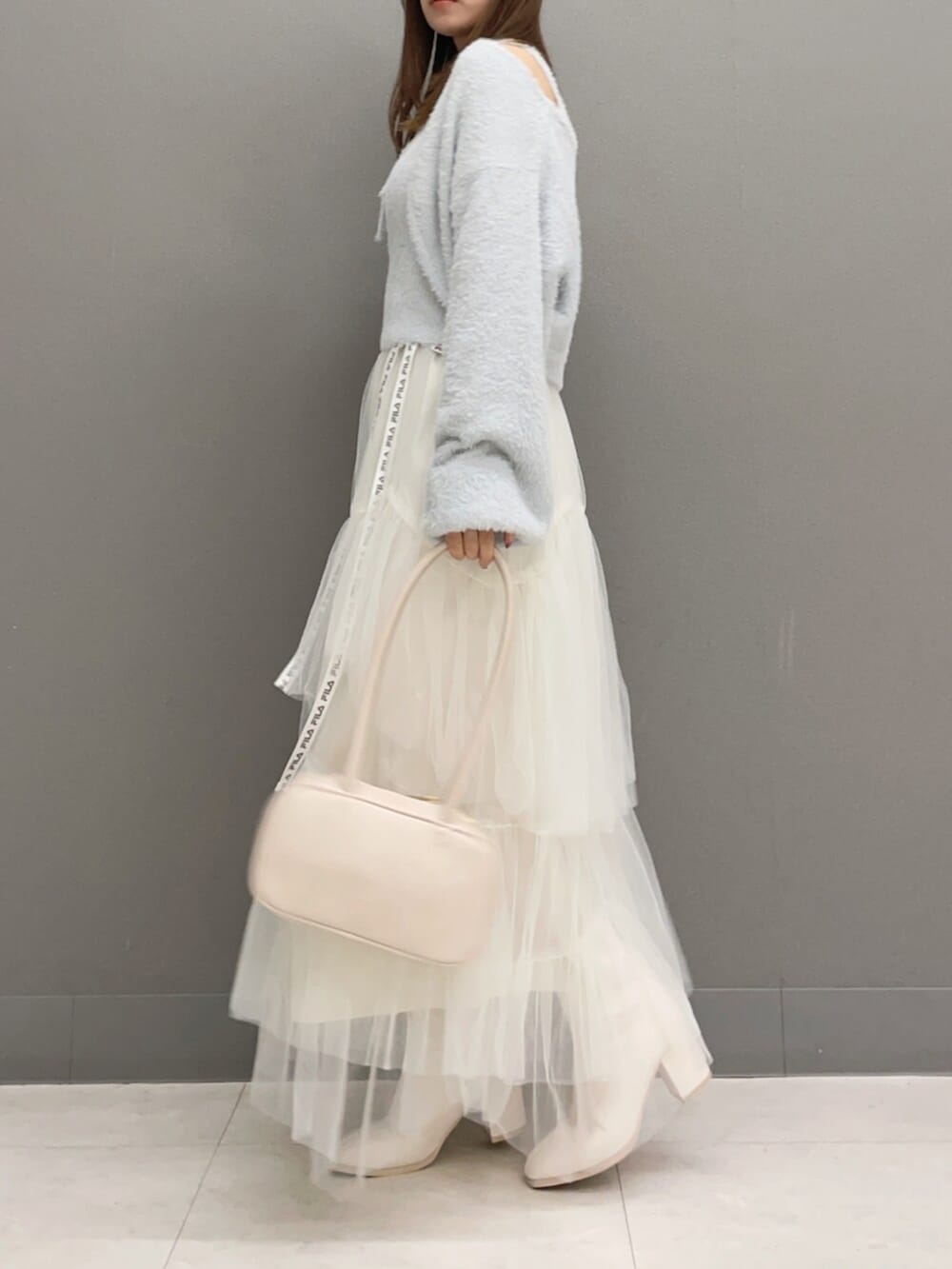 ホワイト系のハンドバッグ、ホワイト系のブーツ、グレー系のキャミソールを着用したレディースの秋コーディネートの4枚目の写真