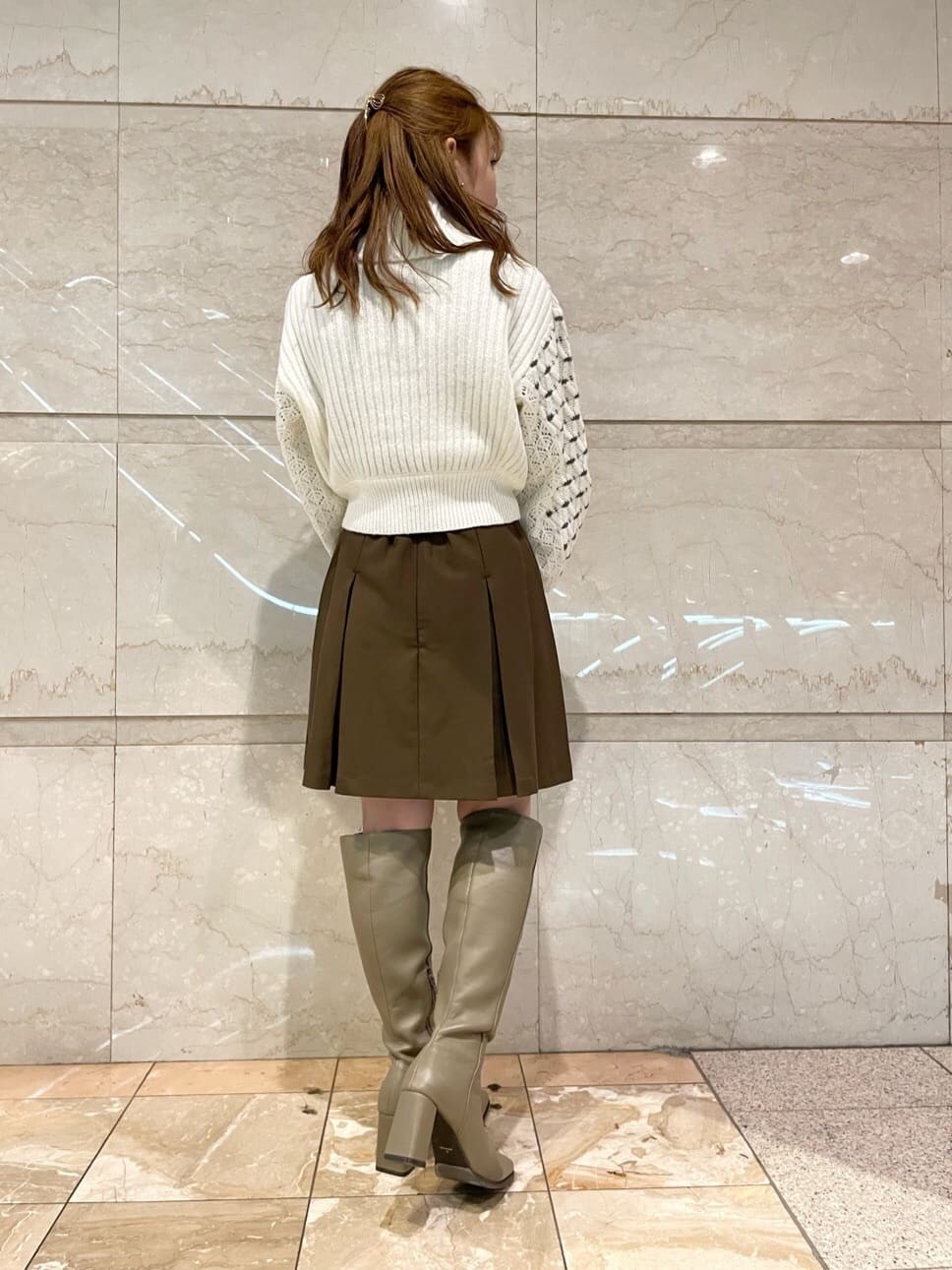 ブラウン系のスカート、ベージュ系のブーツ、ホワイト系のニット/セーターを着用したレディースの秋コーディネートの3枚目の写真