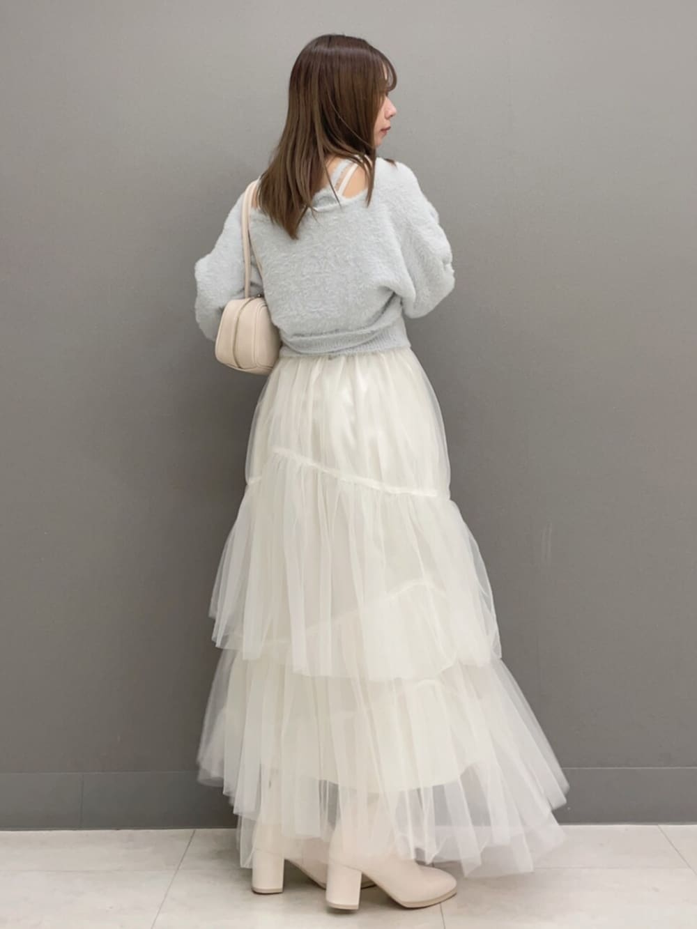 ホワイト系のハンドバッグ、ホワイト系のブーツ、グレー系のキャミソールを着用したレディースの秋コーディネートの3枚目の写真