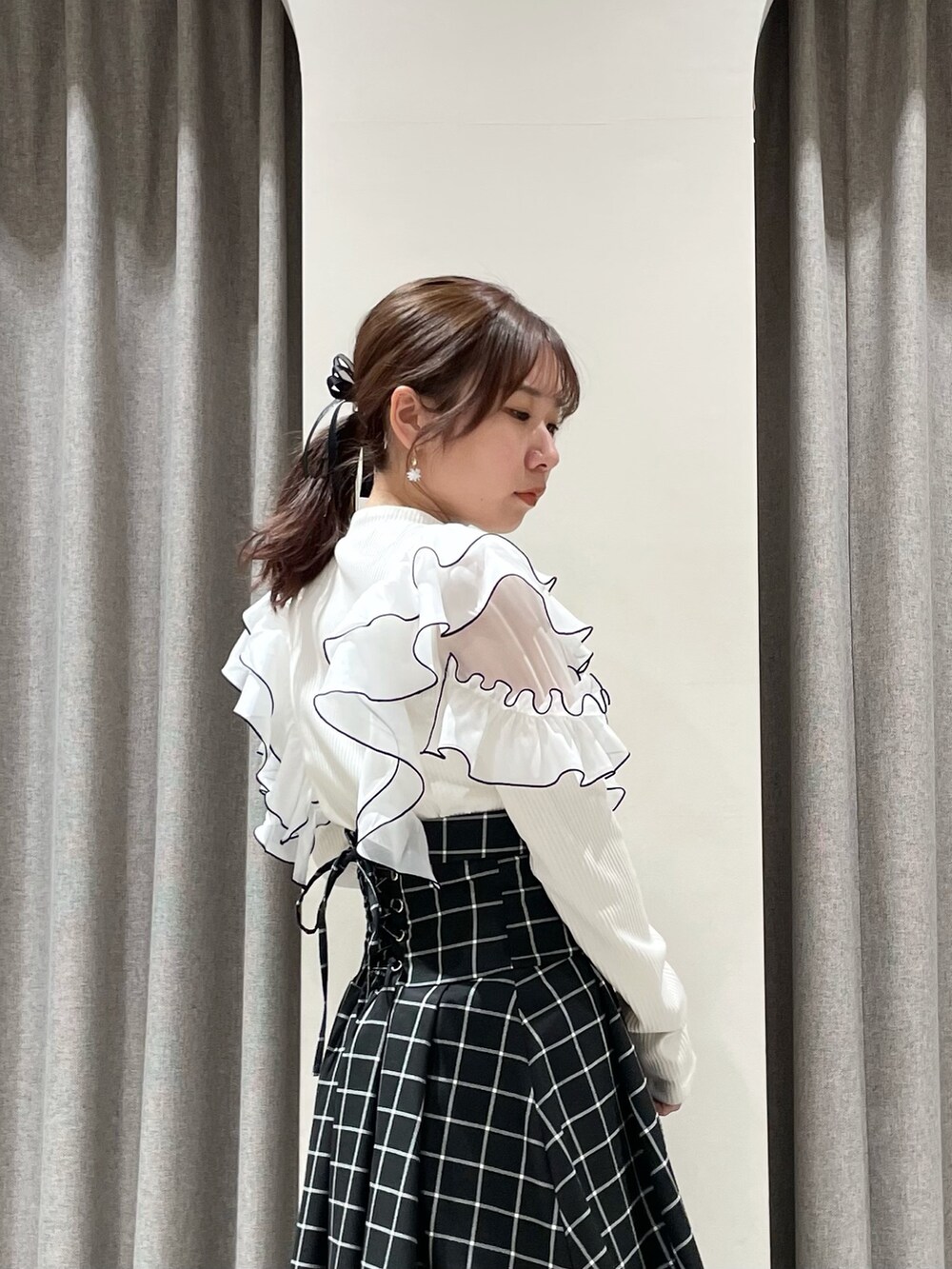 ブラック系のスカート、ホワイト系のTシャツ/カットソー、ブラック系のブーツを着用したレディースの春コーディネートの6枚目の写真