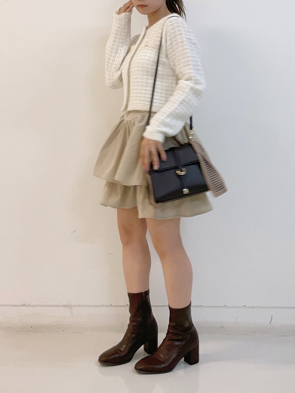 ホワイト系のカーディガン/ボレロ、ホワイト系のスカート、ブラウン系のショルダーバッグを着用したレディースの秋コーディネートの3枚目の写真