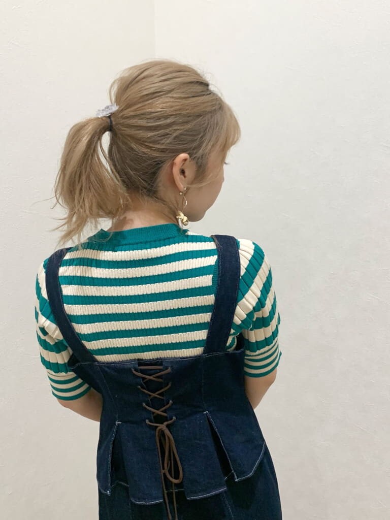 ホワイト系のスニーカー、ブルー系のジャンパースカート、グリーン系のニット/セーターを着用したレディースの春コーディネートの4枚目の写真