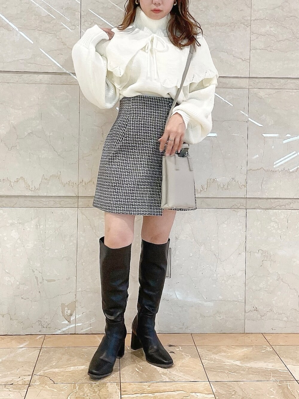 ホワイト系のニット/セーター、ブルー系のスカート、ブラック系のブーツを着用したレディースの秋コーディネートの4枚目の写真