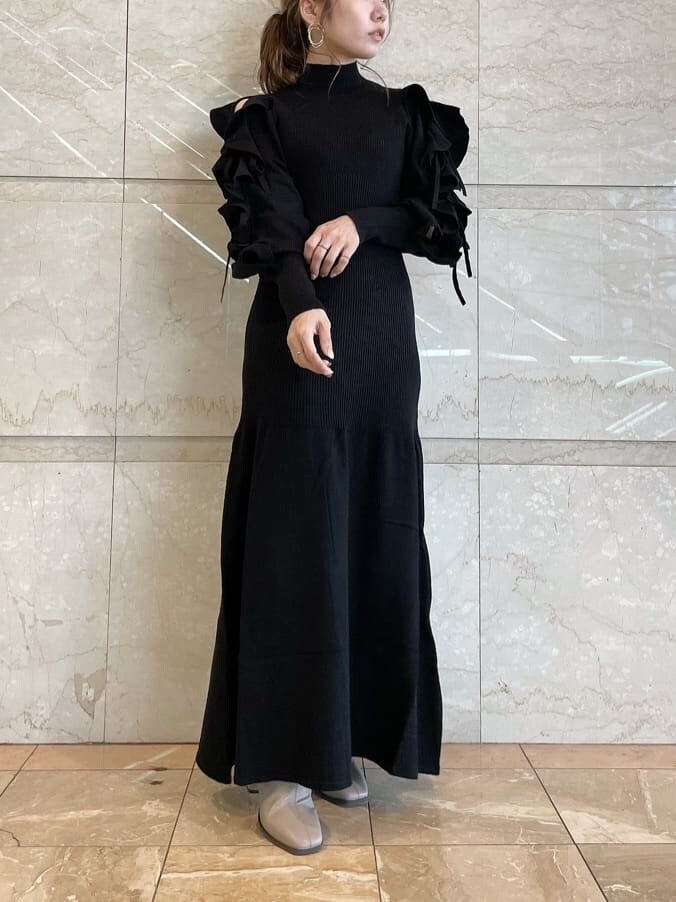 ベージュ系のブーツ、ブラック系のワンピース、ゴールド系のピアス（両耳用）を着用したレディースの秋コーディネートの2枚目の写真