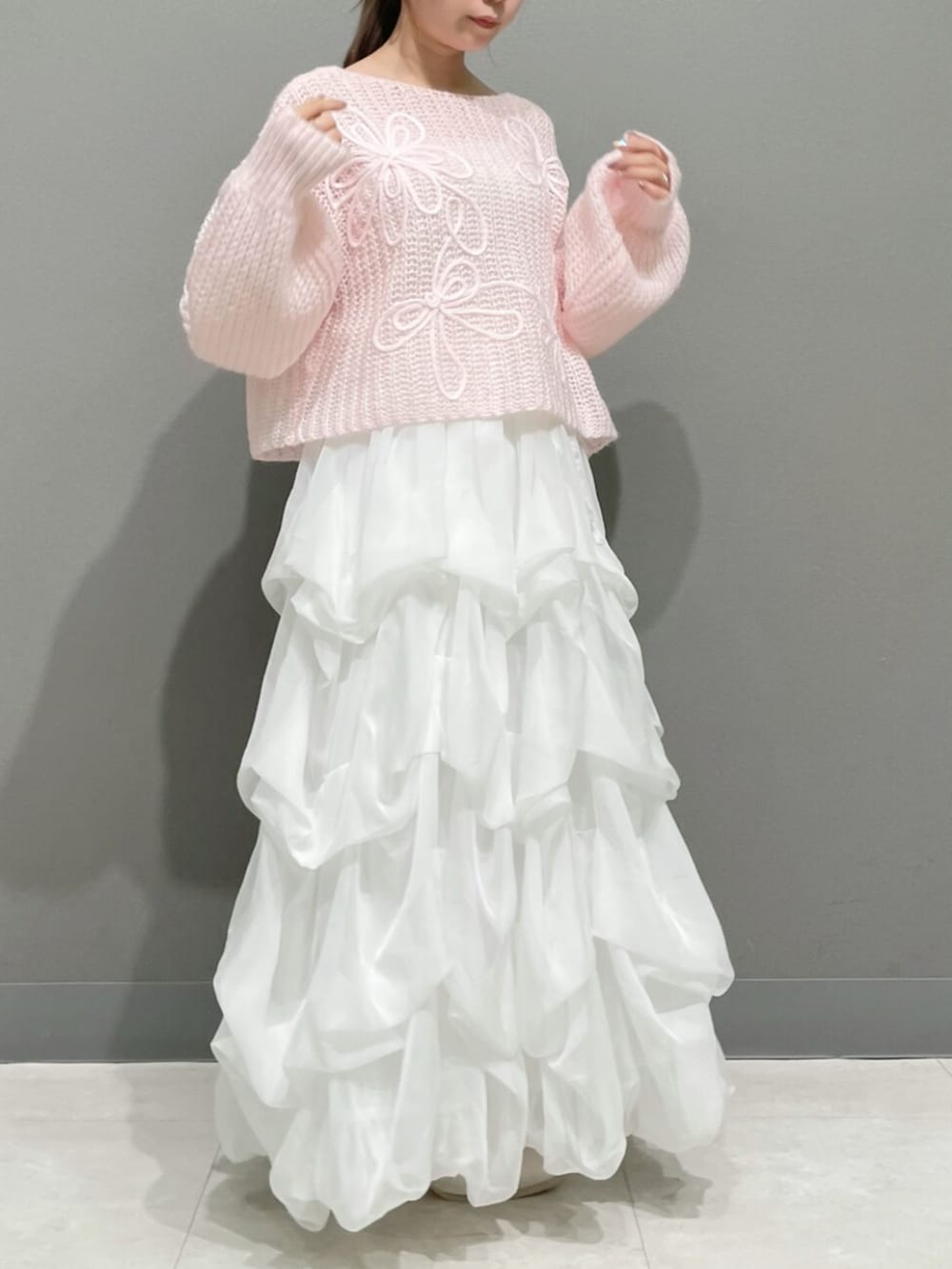 ピンク系のニット/セーター、ホワイト系のスカート、ホワイト系のブーツを着用したレディースの秋コーディネートの3枚目の写真