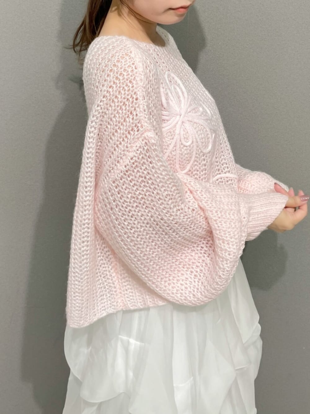 ピンク系のニット/セーター、ホワイト系のスカート、ホワイト系のブーツを着用したレディースの秋コーディネートの6枚目の写真