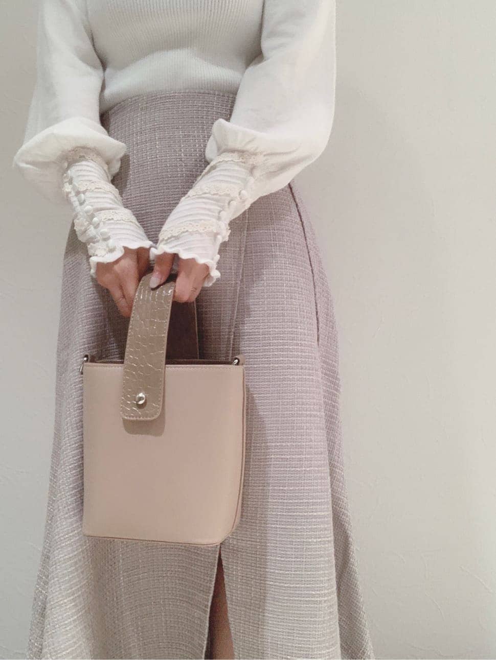 グレー系のブーツ、グレー系のスカート、ベージュ系のハンドバッグを着用したレディースの秋コーディネートの2枚目の写真