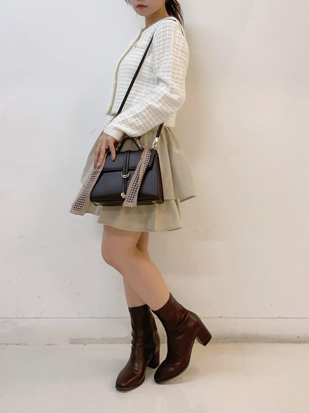 ホワイト系のカーディガン/ボレロ、ホワイト系のスカート、ブラウン系のショルダーバッグを着用したレディースの秋コーディネートの5枚目の写真