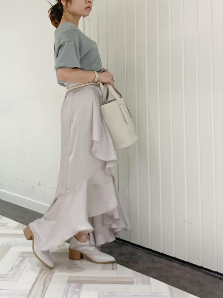 グレー系のスカート、グリーン系のニット/セーター、ホワイト系のローファーを着用したレディースの春コーディネートの2枚目の写真