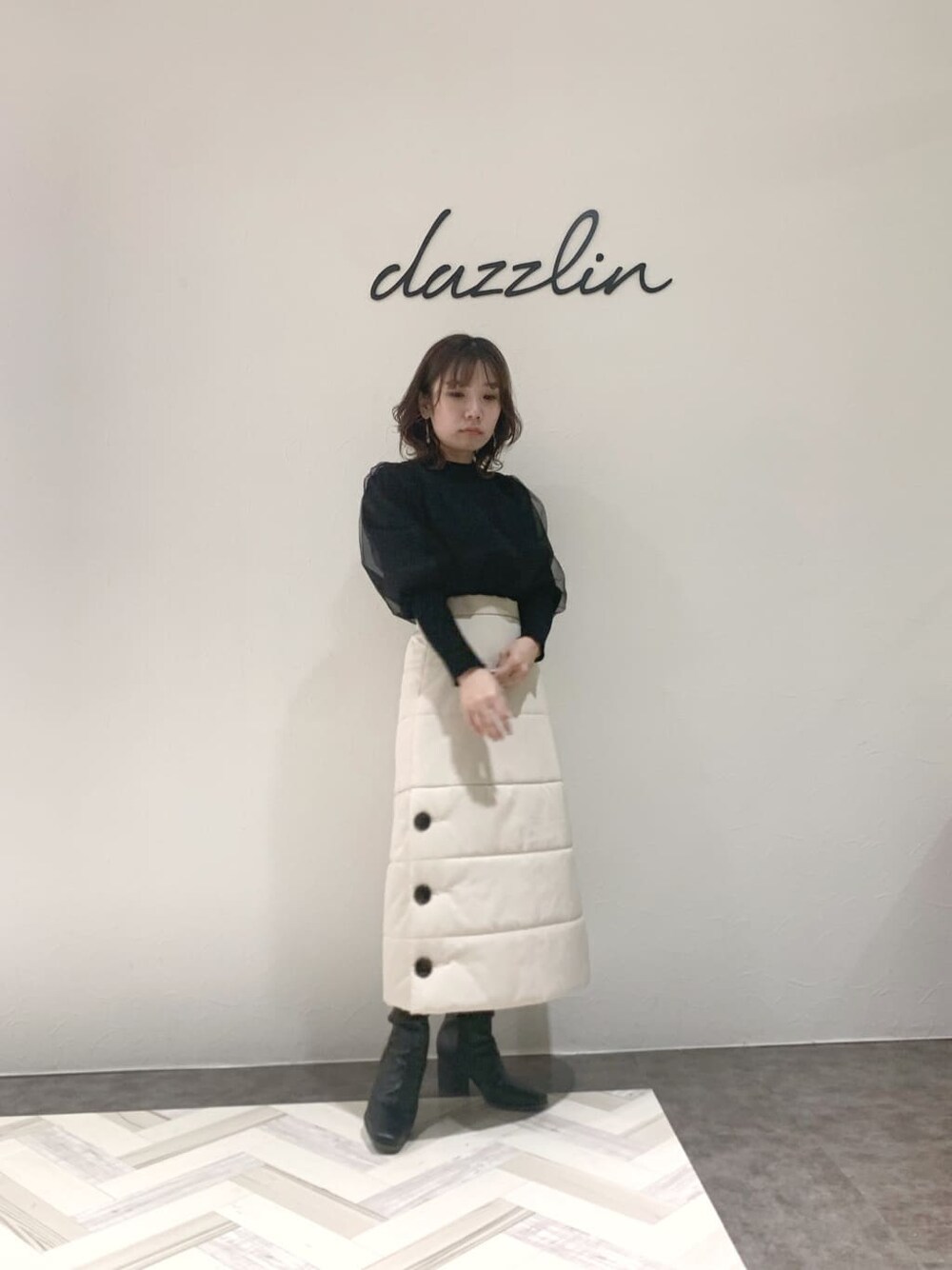 ブラック系のブーツ、ブラック系のニット/セーター、ホワイト系のスカートを着用したレディースの秋コーディネートの2枚目の写真