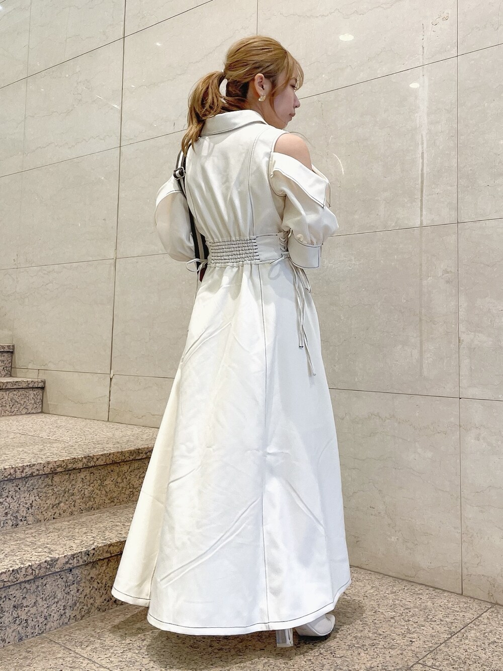 ホワイト系のワンピース、ホワイト系のパンプス、イエロー系のハンドバッグを着用したレディースの冬コーディネートの4枚目の写真