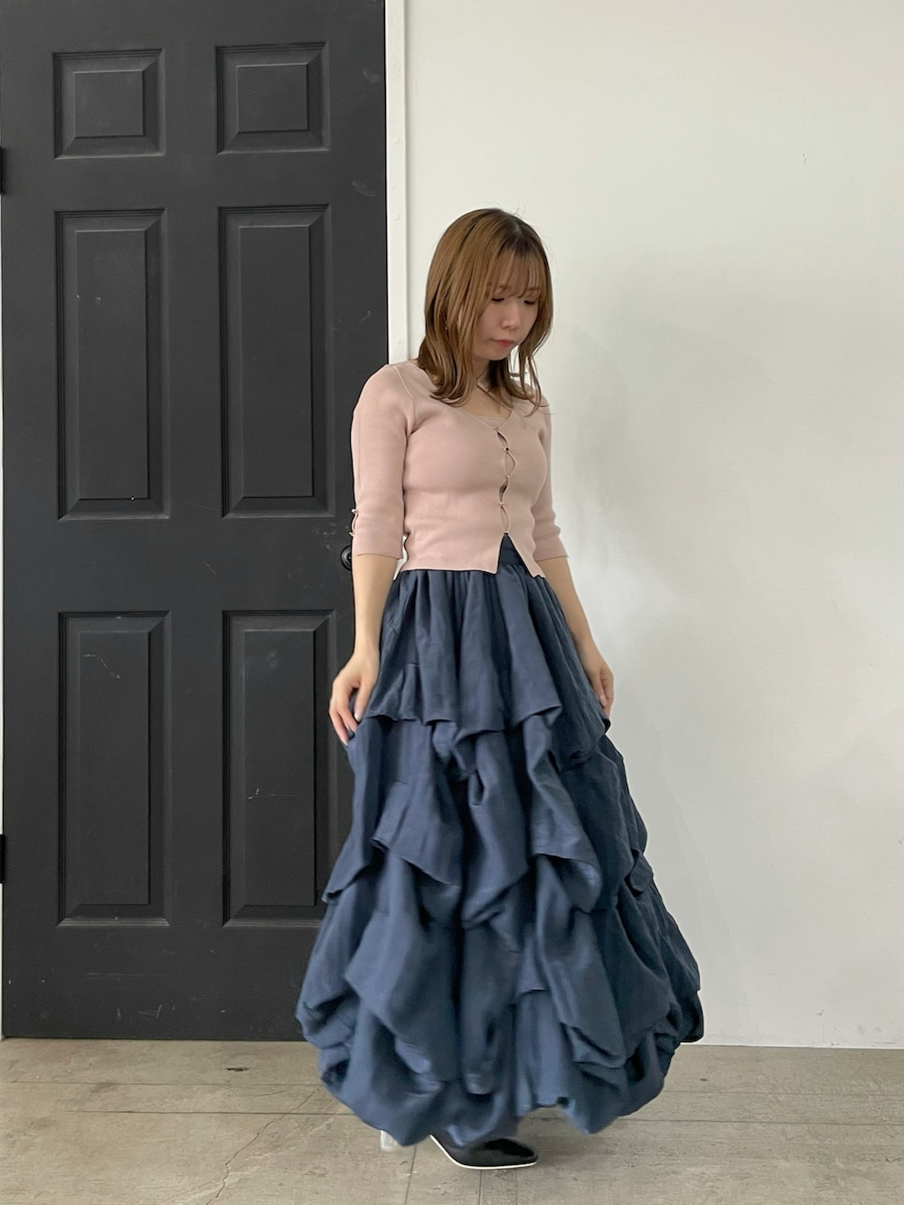 ピンク系のニット/セーター、ブルー系のスカート、ブラック系のパンプスを着用したレディースの春コーディネートの3枚目の写真