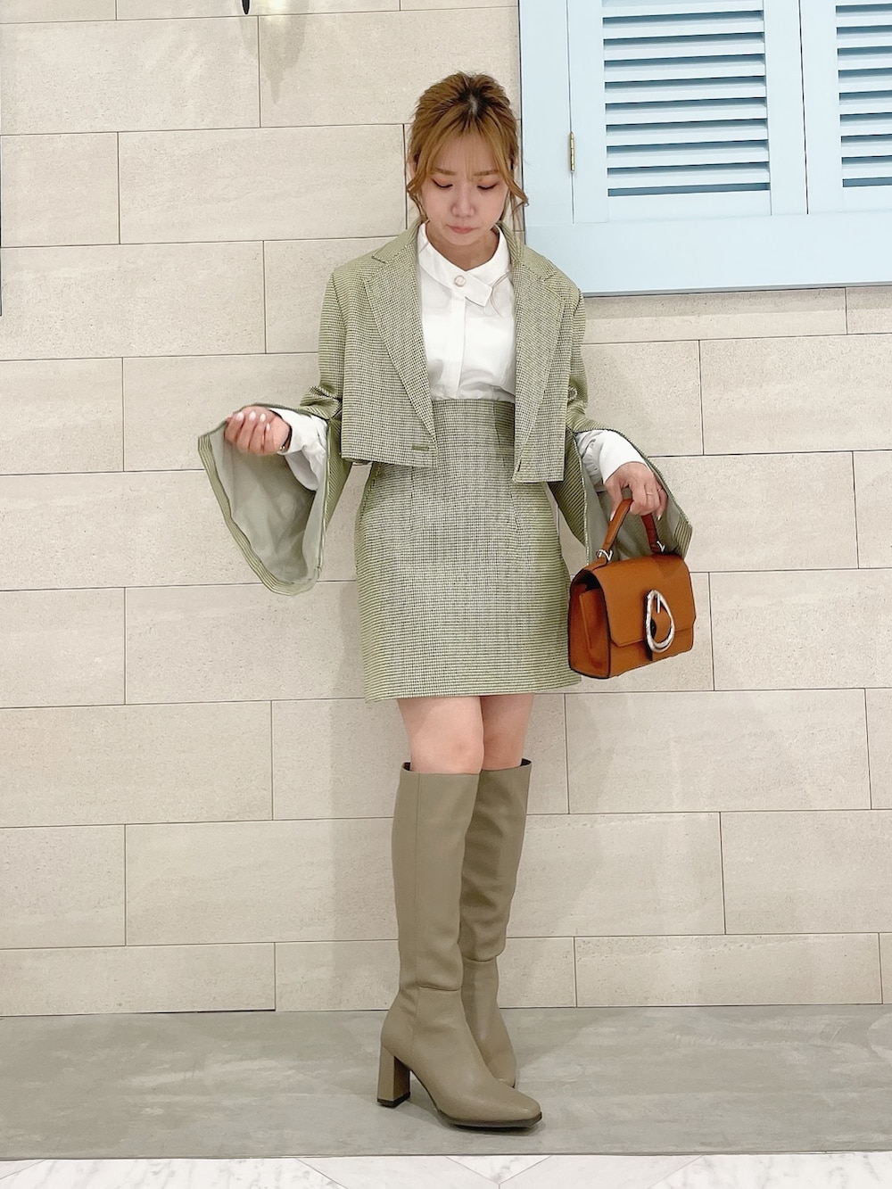 グリーン系のテーラードジャケット、ホワイト系のシャツ/ブラウス、グリーン系のスカートを着用したレディースの冬コーディネートの2枚目の写真