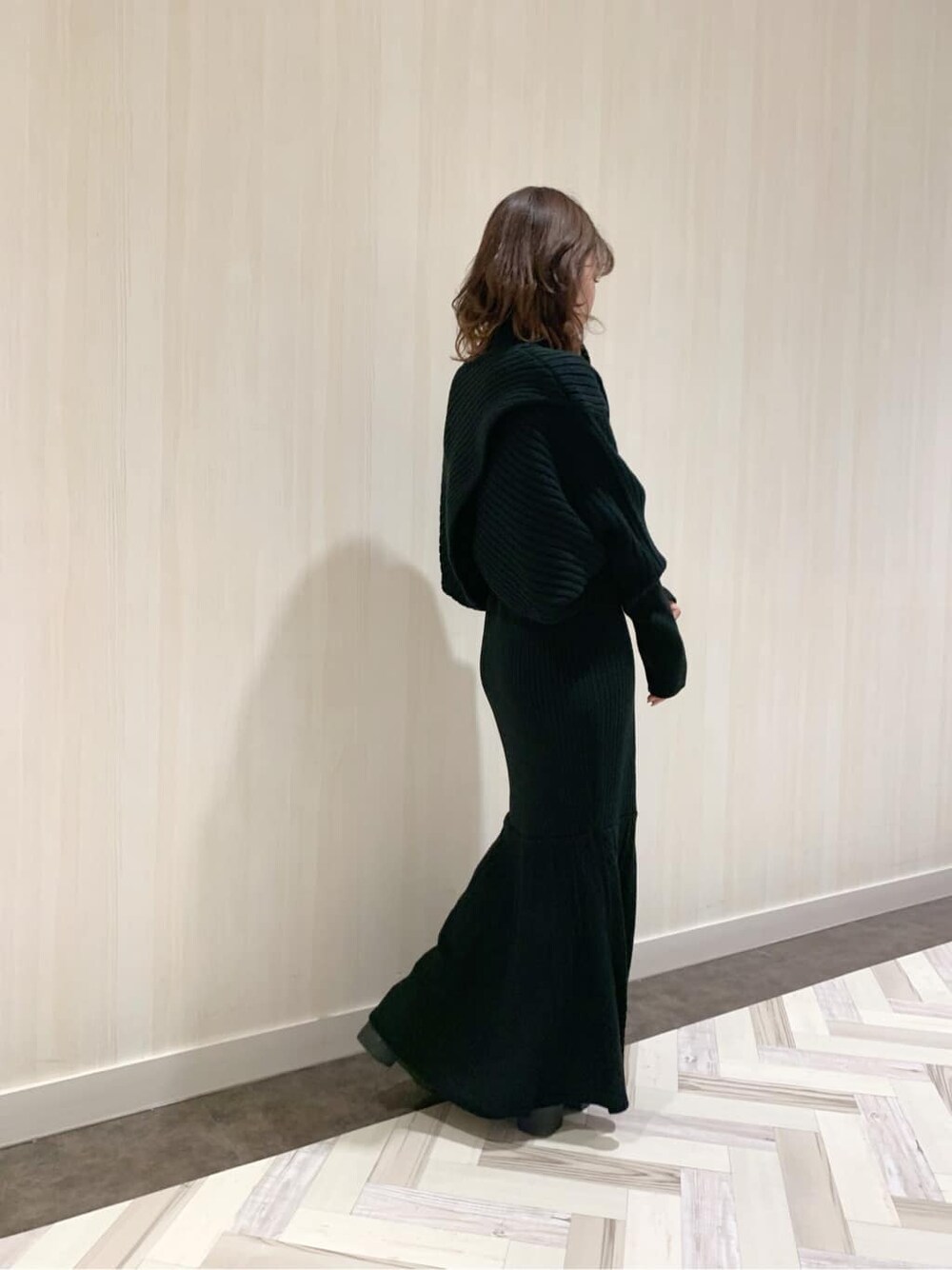 ブラック系のスカート、ブラック系のブーツ、ブラック系のニット/セーターを着用したレディースの秋コーディネートの2枚目の写真